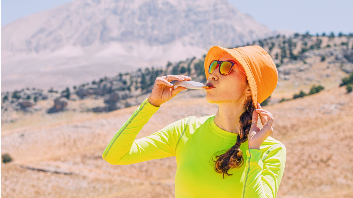 Young woman consuming an energy gel while hiking